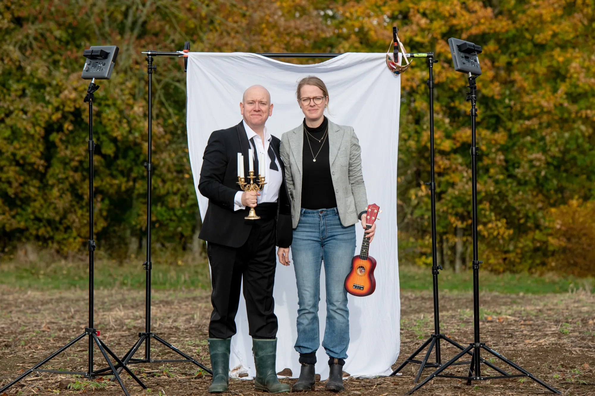 Fanny och Olof på ett fält framför ett vitt skynke med rekvisita